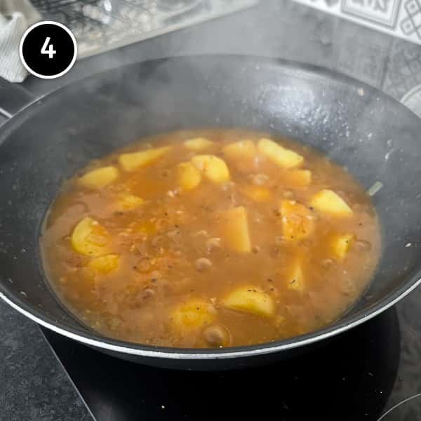 Potatoes simmering in a pan of stock/broth