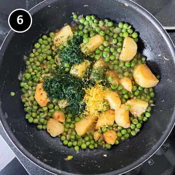 Peas and potatoes with dill and lemon zest in a large pan. Taken from overhead.