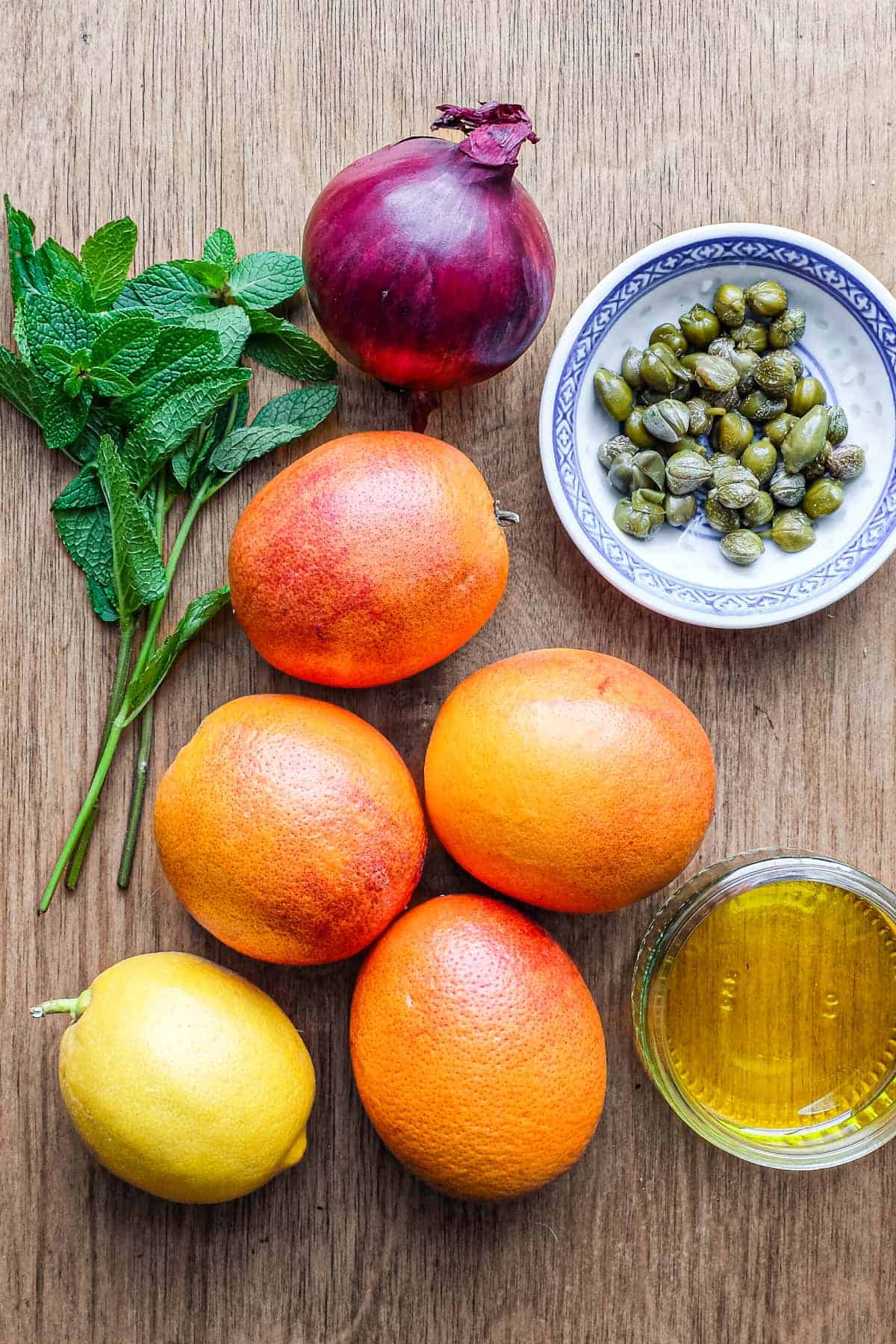 The ingredients for blood orange and caper salad: Blood oranges, lemon, olive oil, mint and capers.