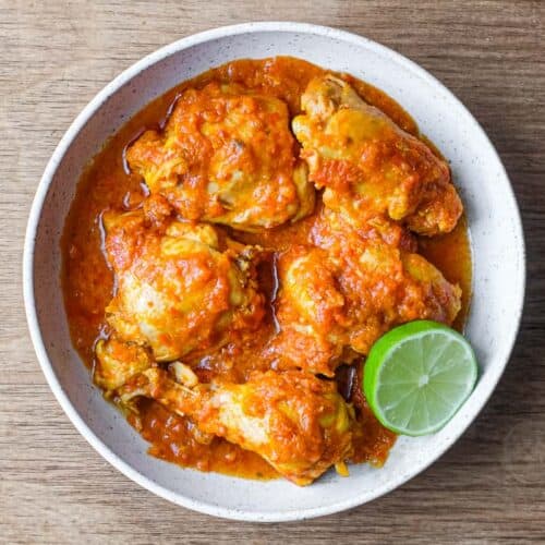 A bowl of Indonesian Ayam Rica Rica. A lime segment sits alongside as a garnish.