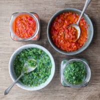 Two bowls and two jars of Middle Eastern Shatta Sauce. A red variety and green variety.