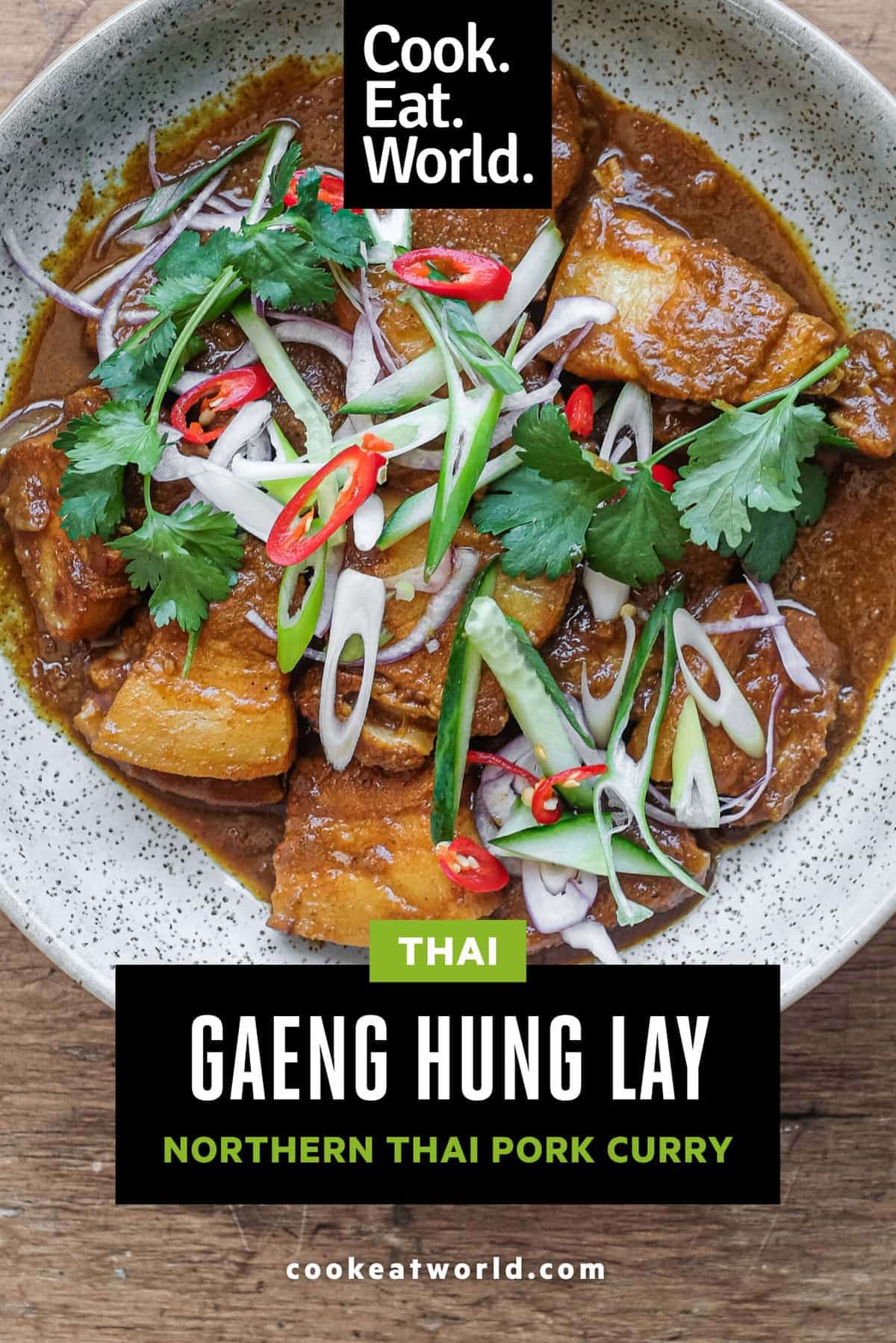 A bowl of Gaeng Hung Lay (Thai Pork Curry) garnished with herbs, spring onion, chilli and shallots