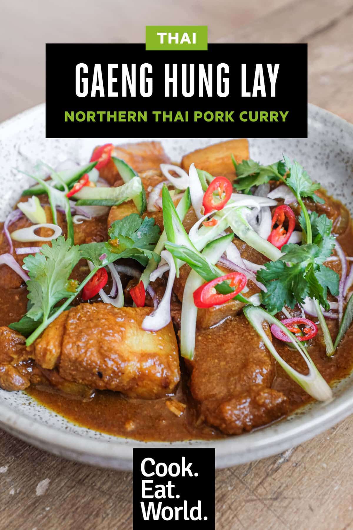 A bowl of Gaeng Hung Lay (Thai Pork Curry) garnished with herbs, spring onion, chilli and shallots