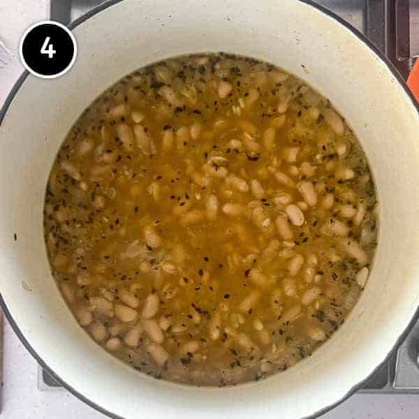 A pan with the finished garlic soup with beans and bacon