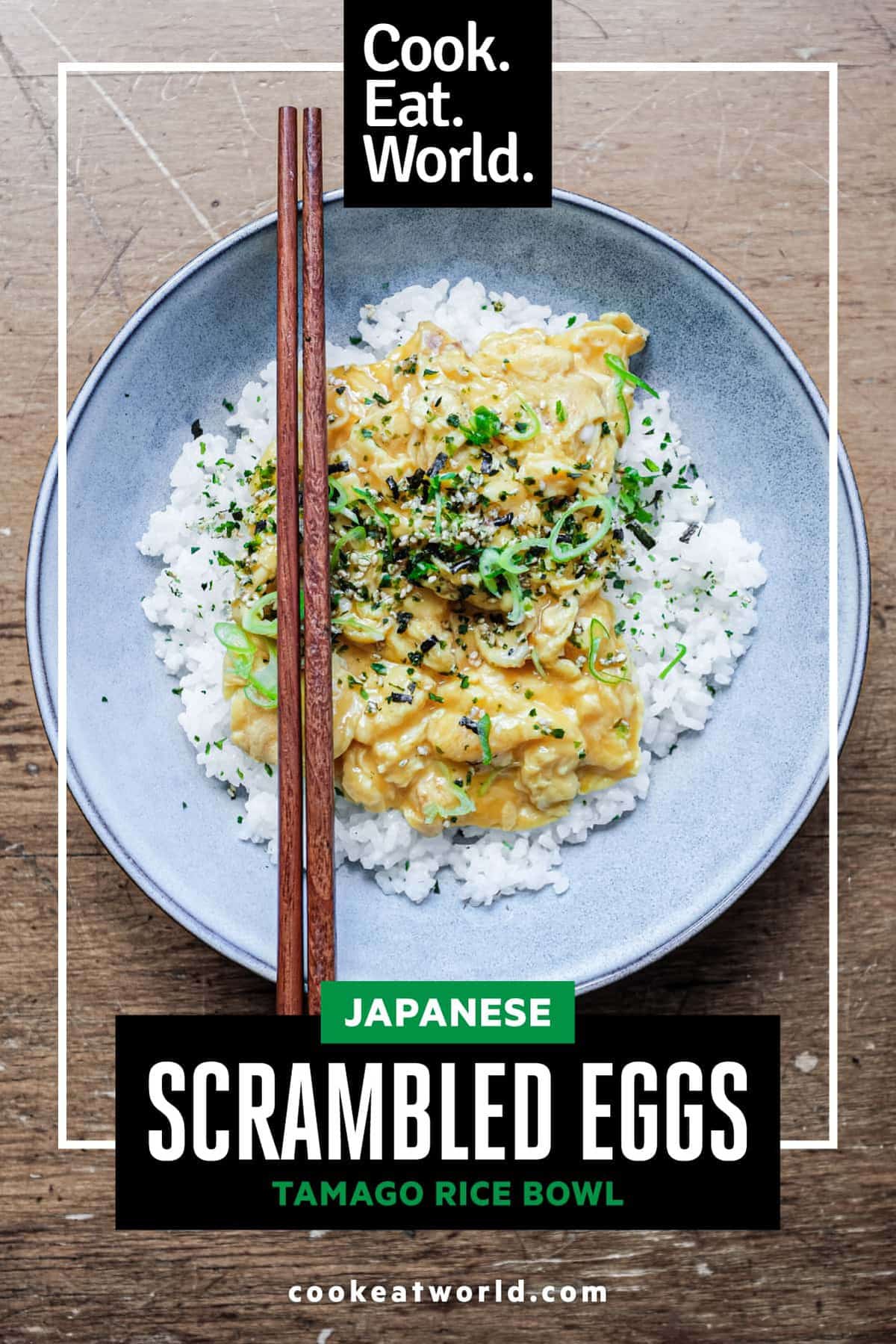 A bowl of Japanese scrambled eggs over rice and garnished with rice seasoning and spring onions. Wooden chopsticks sit on the bowl.