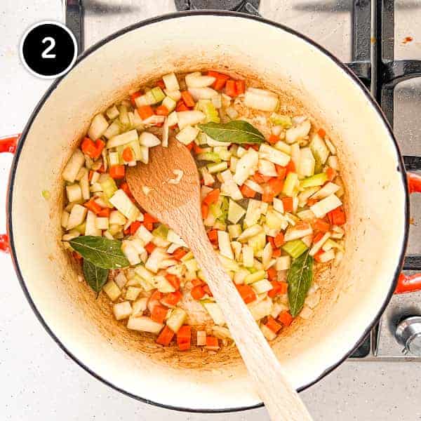 Onion, celerym carrot, garlic and bay leaves frying in a large pan
