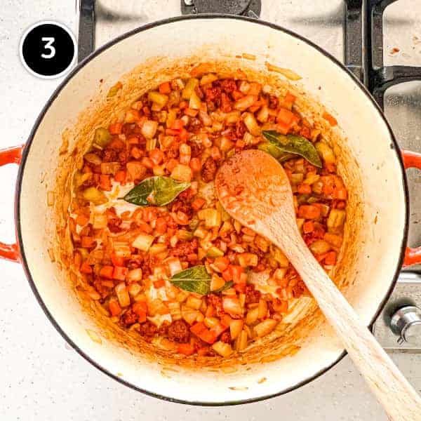 Vegetables and nduja sausage frying in a large pan