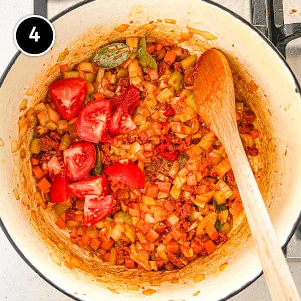 Vegetables and nduja with tomatoes frying in a pan