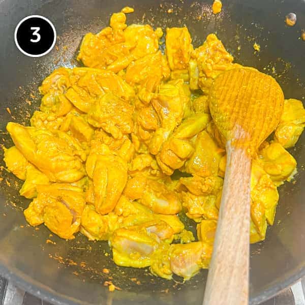 chicken frying in a pan with turmeric