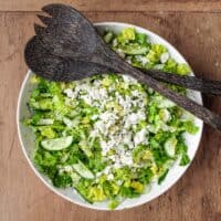 A bowl of Greek lettuce salad with salad servers