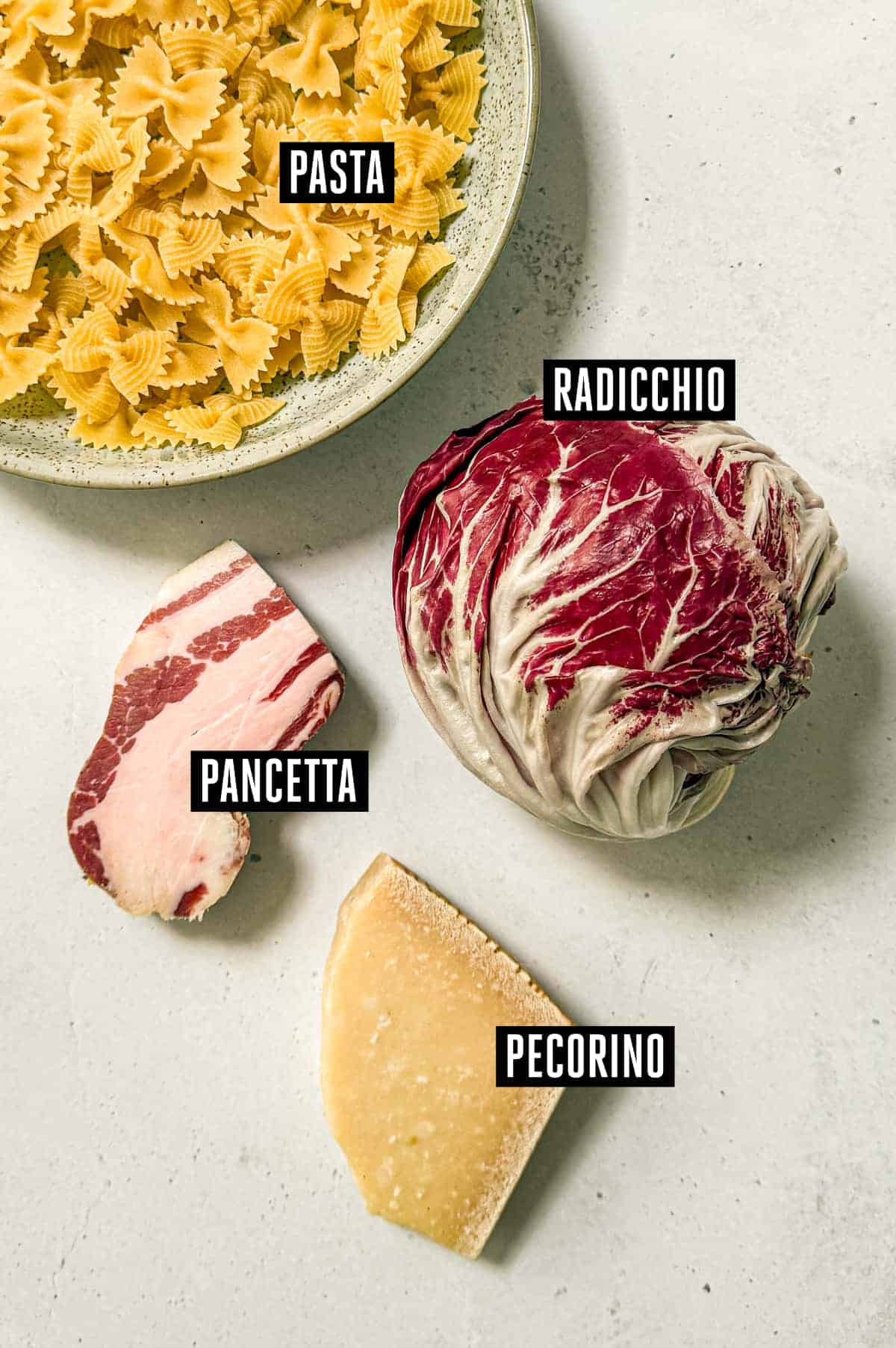 Pasta Al Radicchio & Pancetta | cookeatworld.com A small bowl of farfalle pasta alongside a radicchio, slice of pancetta and a small block of pecorino cheese.