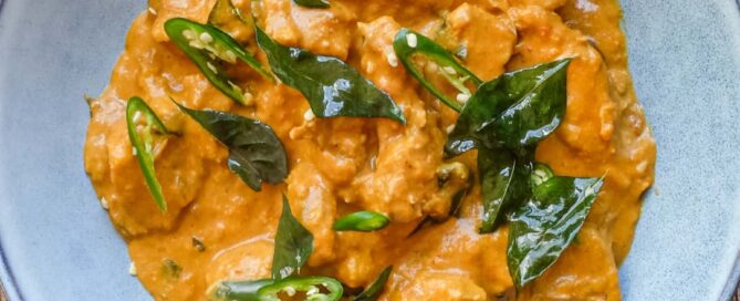 A bowl of Andhra chicken curry garnished with fried curry leaves