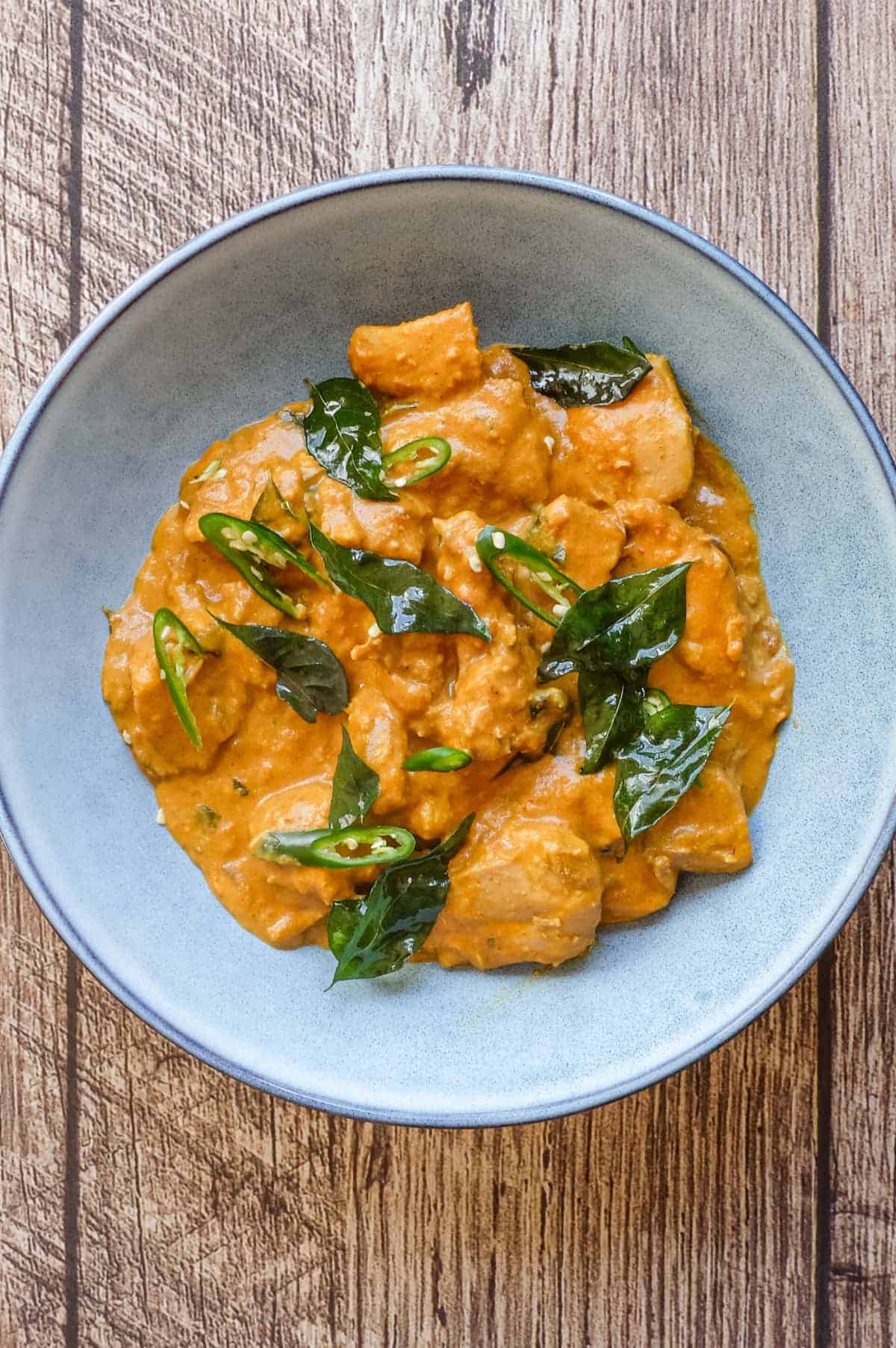 A bowl of Andhra chicken curry garnished with fried curry leaves