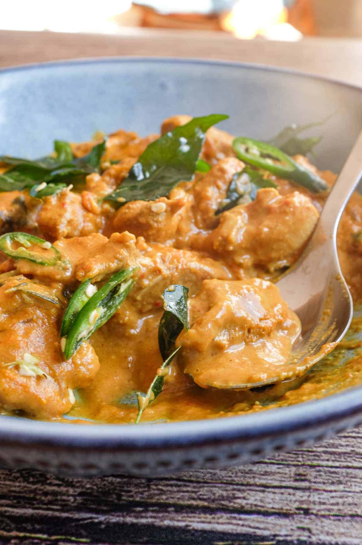 A bowl of Andhra chicken curry garnished with fried curry leaves