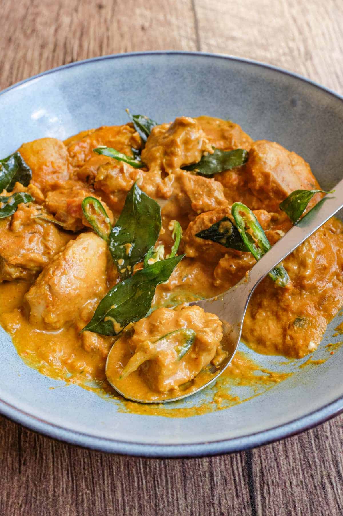 A bowl of Andhra chicken curry garnished with fried curry leaves