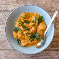 A bowl of Andhra chicken curry garnished with fried curry leaves
