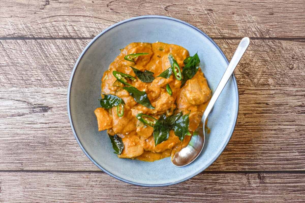 A bowl of Andhra chicken curry garnished with fried curry leaves