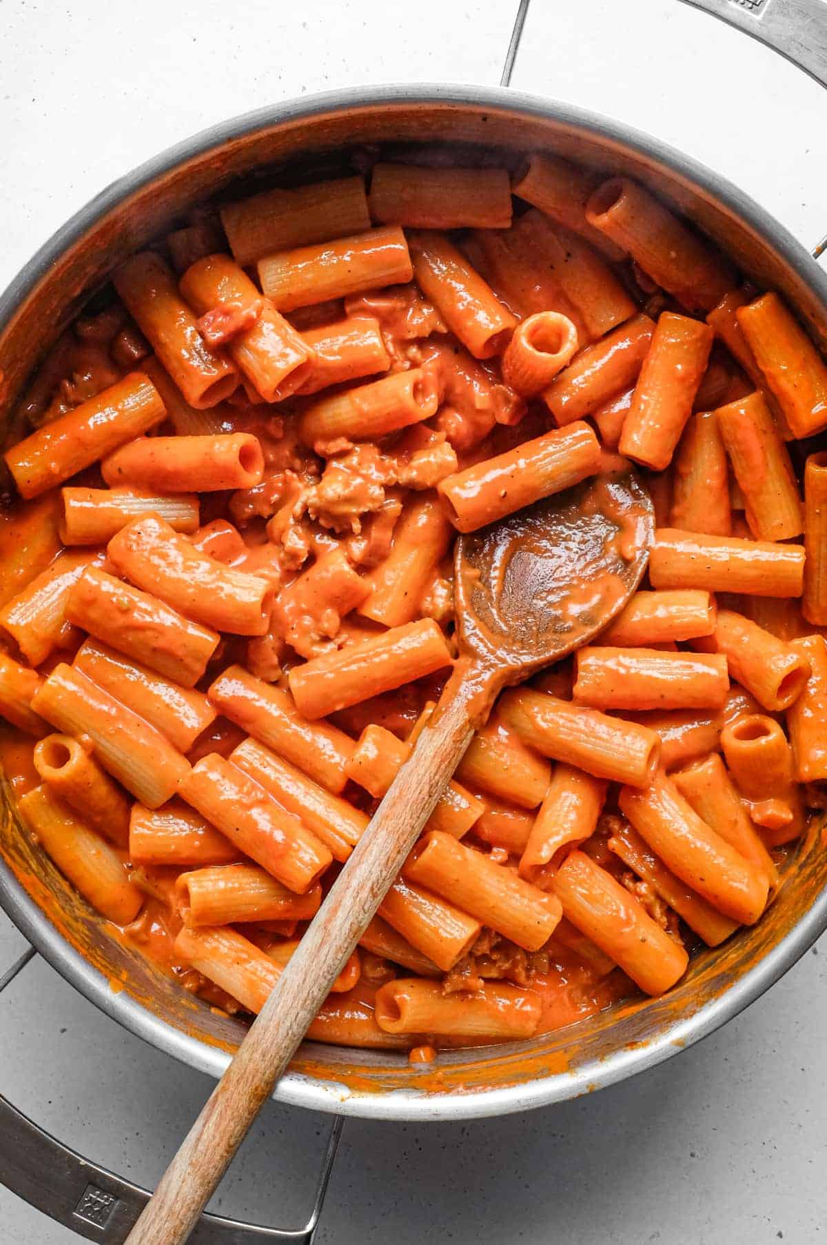 Pasta Alla Zozzona – cookeatworld.com A panof Pasta Alla Zozzona in a rich tomato sauce with a wooden spoon.