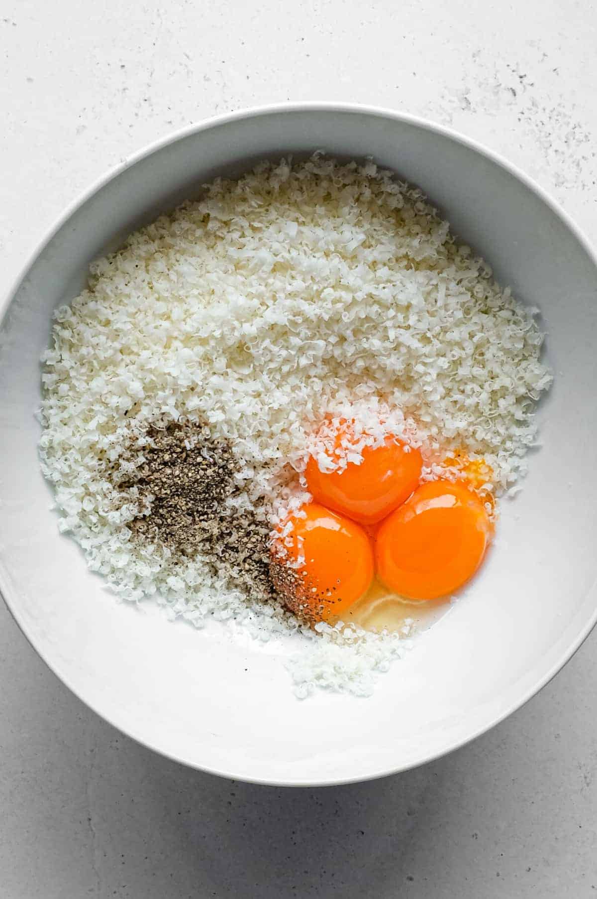 Pasta Alla Zozzona – cookeatworld.com A small bowl holding finely grated pecorino cheese, egg yolks and black pepper.