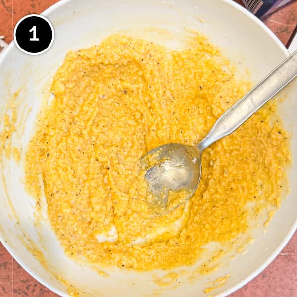 Pasta Alla Zozzona – cookeatworld.com A small bowl with a mixture of egg yolks mixed with pecorino cheese and black pepper with a metal spoon.