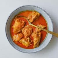 An overhead view of a bowl of Kashmiri chicken rogan josh - a bright red sauce from India's north.