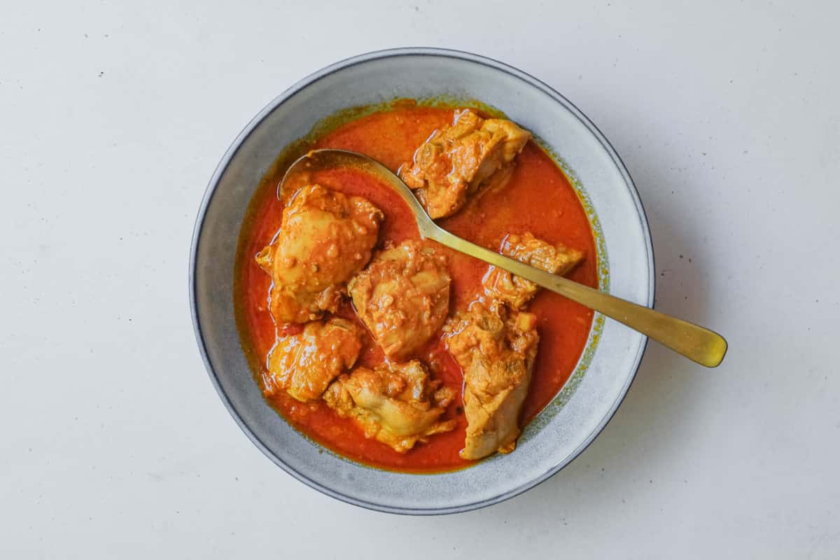 An overhead view of a bowl of Kashmiri chicken rogan josh - a bright red sauce from India's north.
