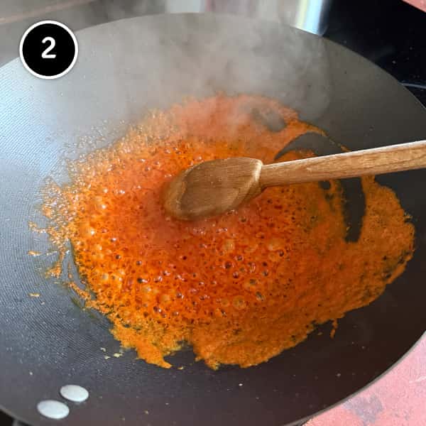 Thai Red Curry Noodles (Easy Vegetarian Recipe) | cookeatworld.com Stirring a Thai red curry paste in a wok.