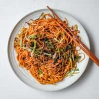 A platter of Chinese scallion oil noodles with some chopsticks.