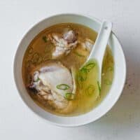 A small bowl with an Asian spoon is filled with Taiwanese Sesame Oil Chicken Soup