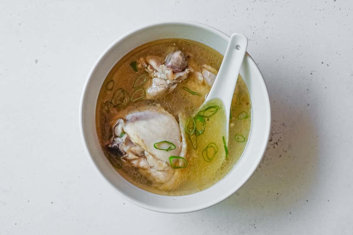 A small bowl with an Asian spoon is filled with Taiwanese Sesame Oil Chicken Soup