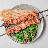 An overhead shot of Turkish chicken kebabs with bread and salad
