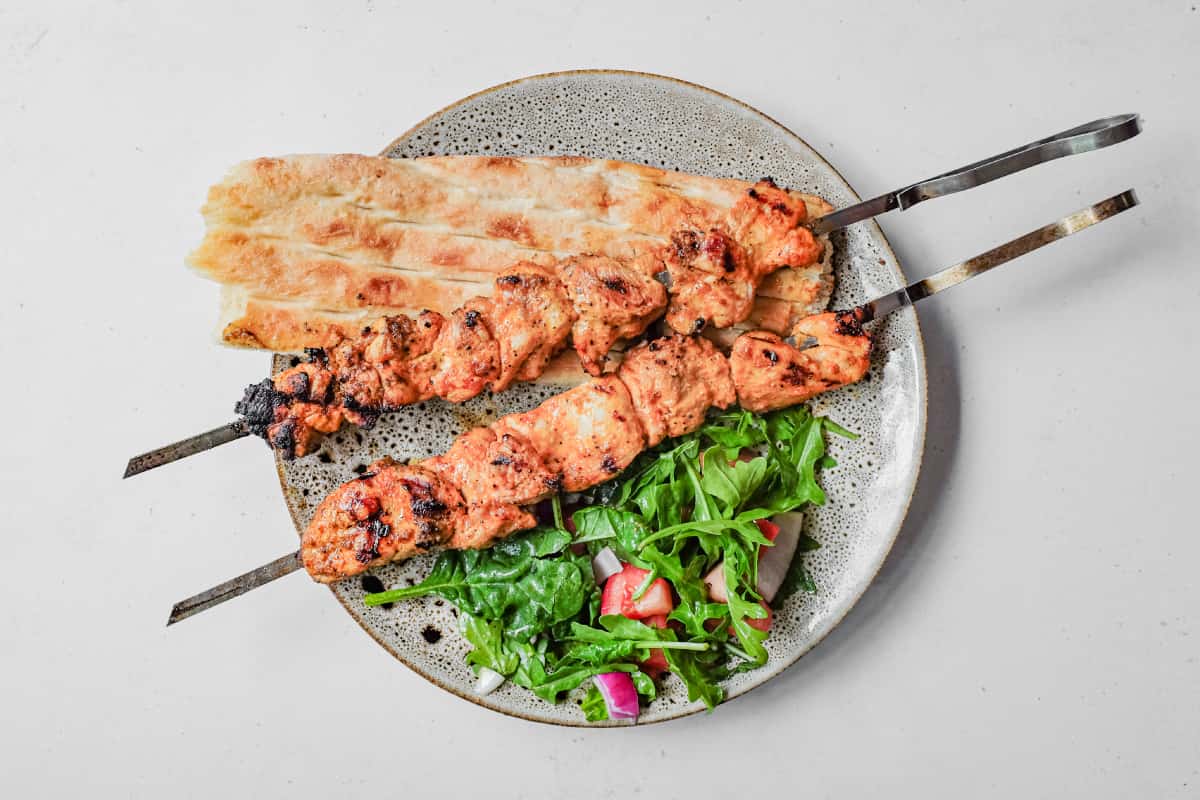 An overhead shot of Turkish chicken kebabs with bread and salad