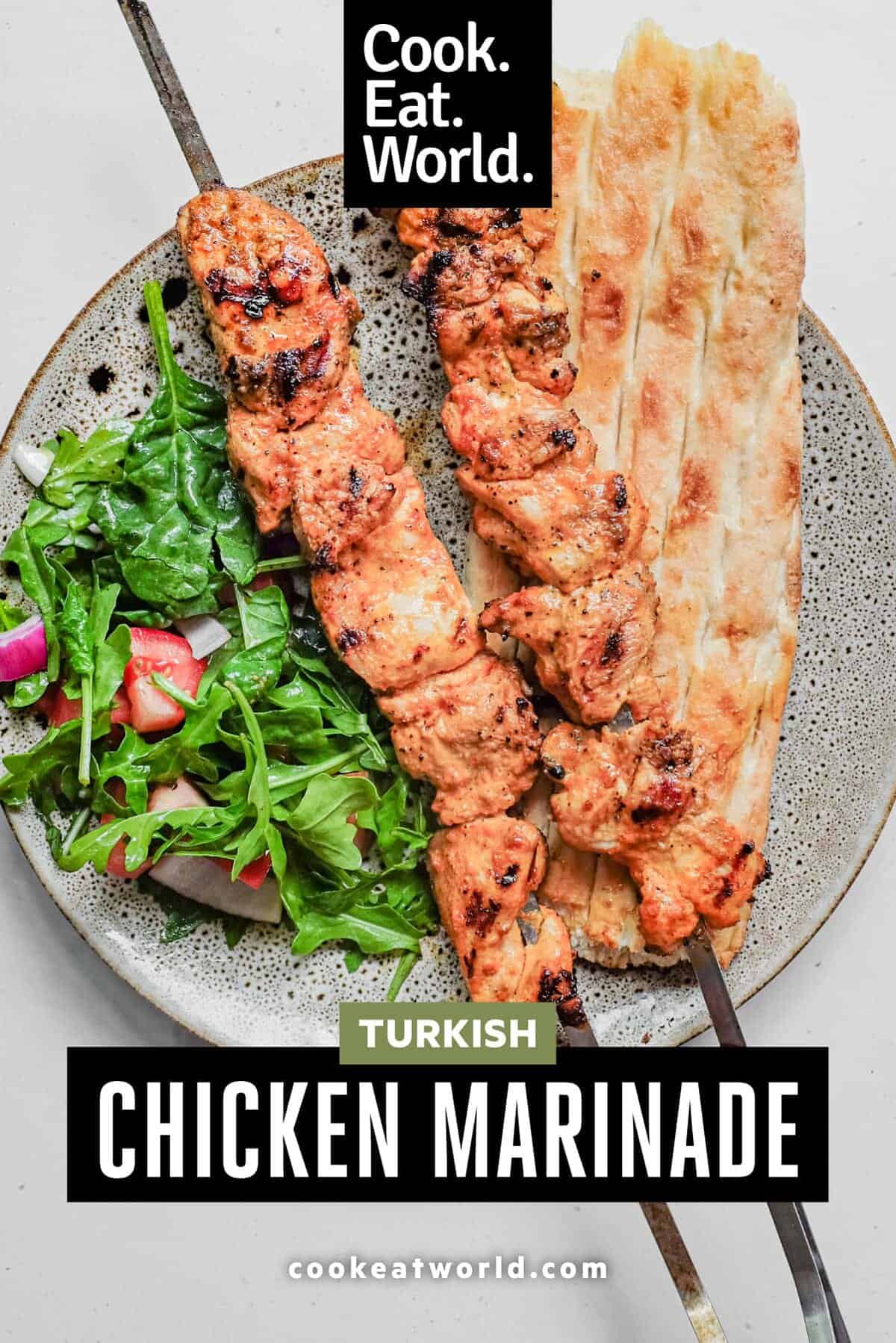 An overhead shot of chicken kebabs with bread and salad.