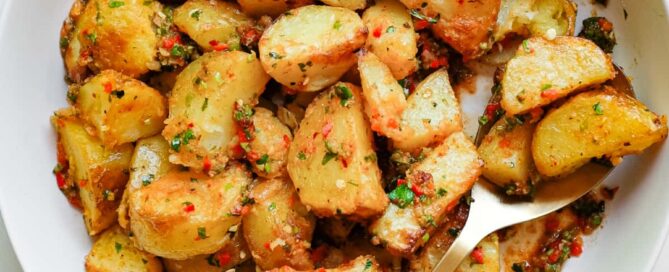 A serving bowl filled with spicy lebanese roast potatoes (batata harra).