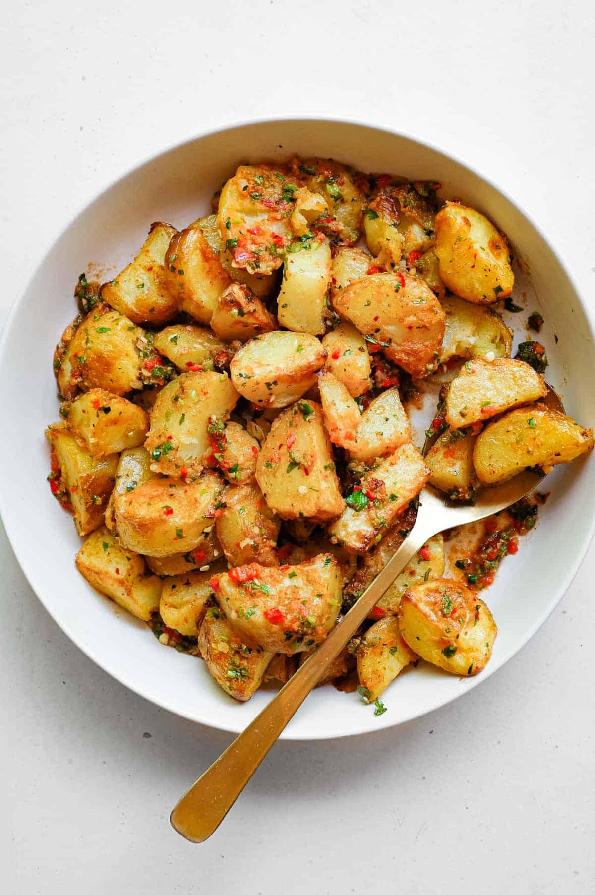 A serving bowl filled with spicy lebanese roast potatoes (batata harra).