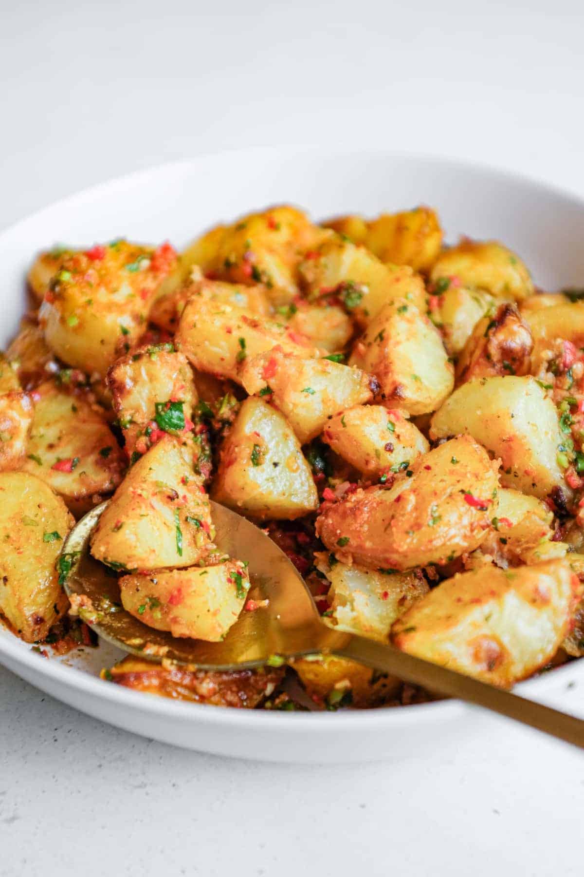 A serving bowl filled with spicy lebanese roast potatoes (batata harra).