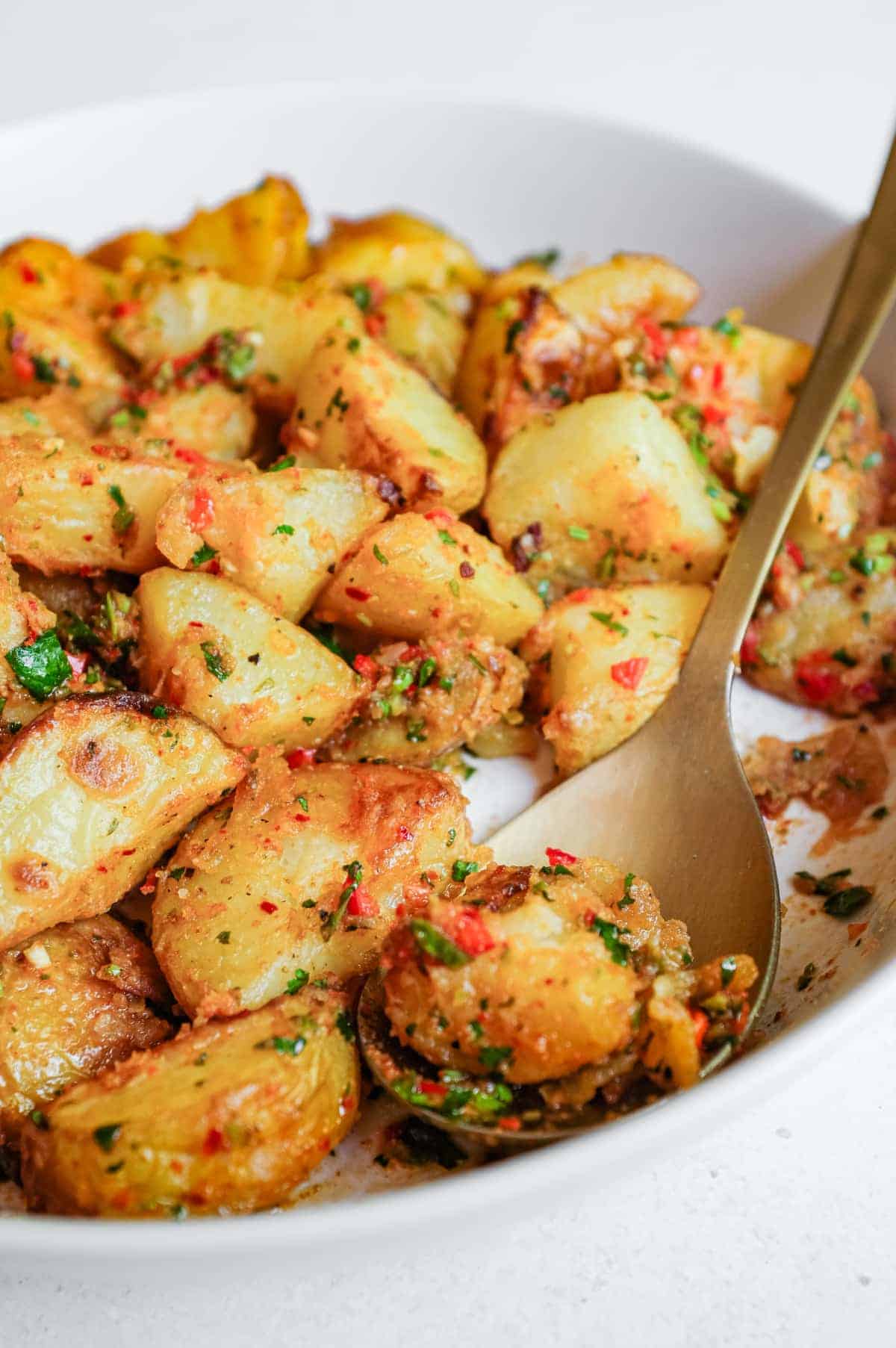 A serving bowl filled with spicy lebanese roast potatoes (batata harra).