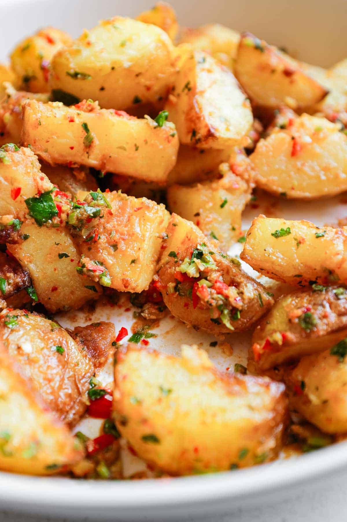 A serving bowl filled with spicy lebanese roast potatoes (batata harra).