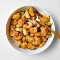 A serving bowl filled with spicy lebanese roast potatoes (batata harra).