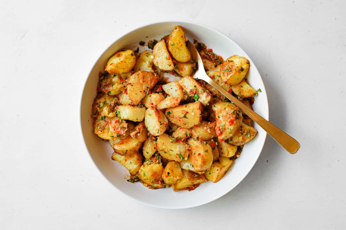 A serving bowl filled with spicy lebanese roast potatoes (batata harra).