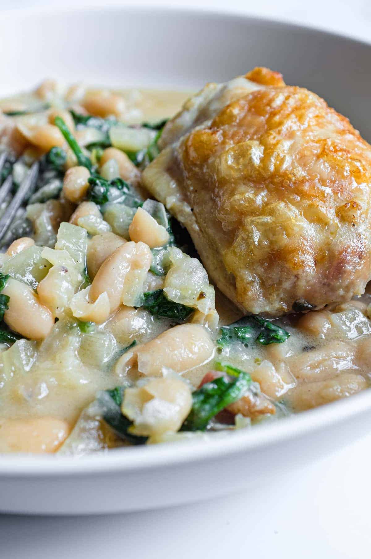 Hearty bowl of Italian chicken and beans with fennel and Parmigiano Reggiano.