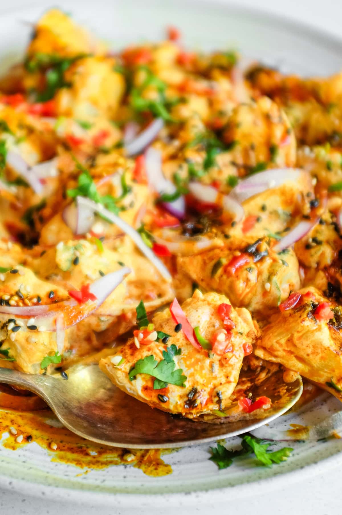A close up image of a platter of creamy Aloo Chukauni, a Nepali potato and yoghurt salad garnished with a vibrant spiced oil