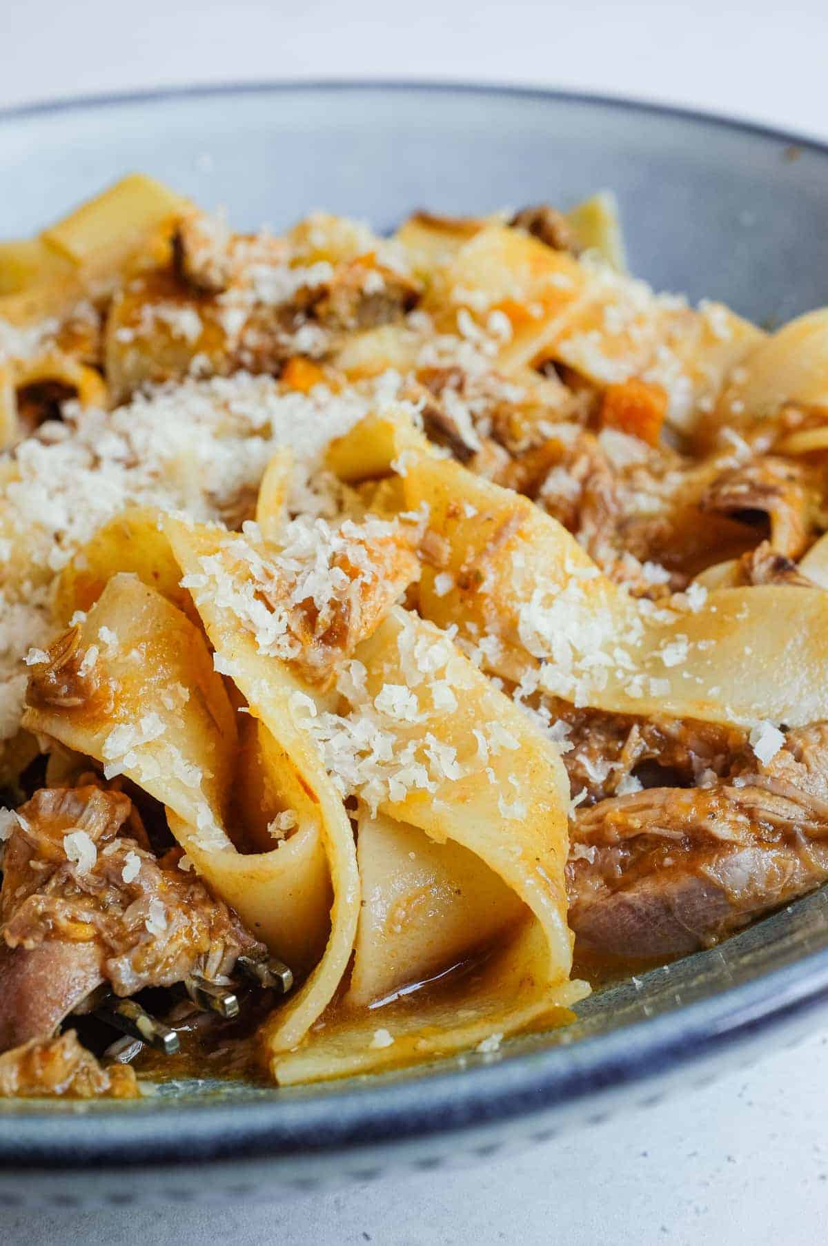The final bowl of duck rag&ugrave; with pappardelle pasta is dusted with freshly grated Parmigiano Reggiano.