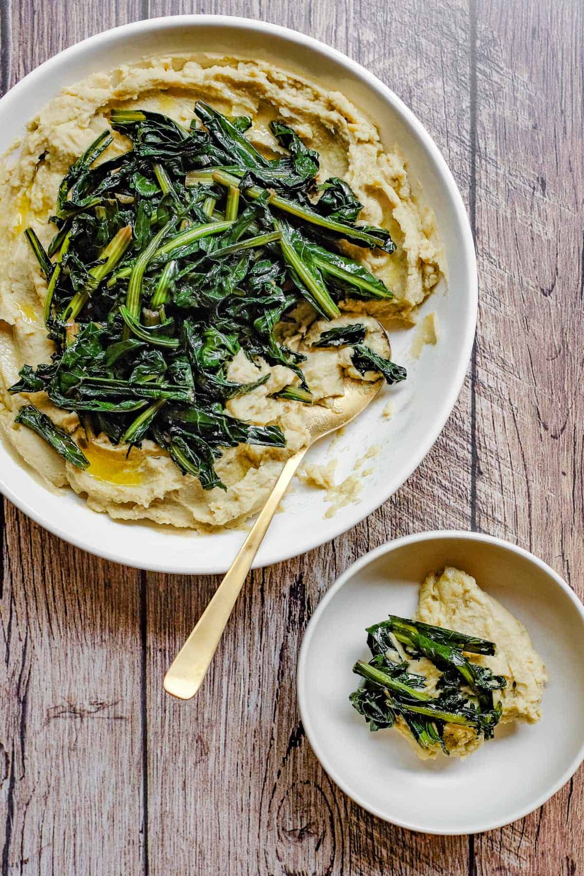 A large platter and smaller bowl with fava bean puree and bitter chicory greens