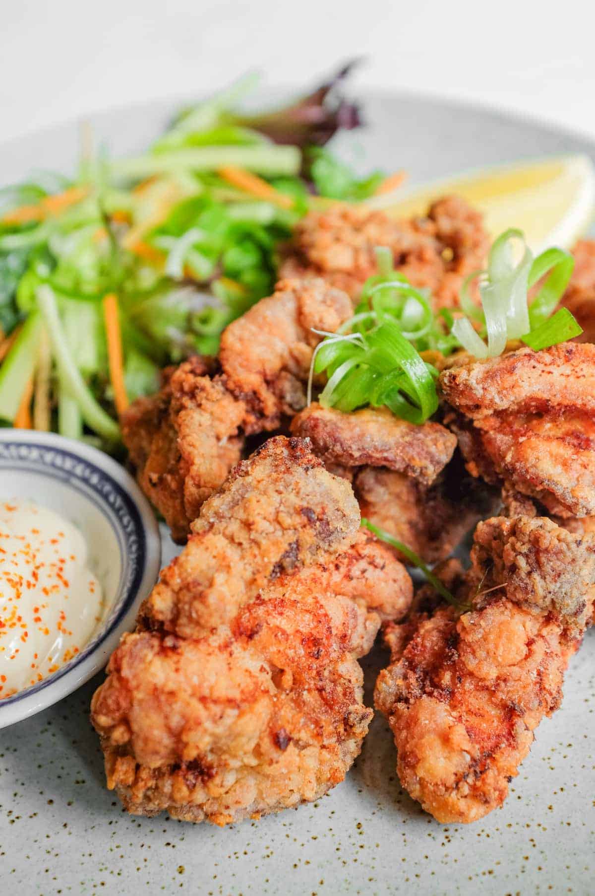 A plate of Japennese karaage chicken with a side salad, lemon wedge, and mayonnaise