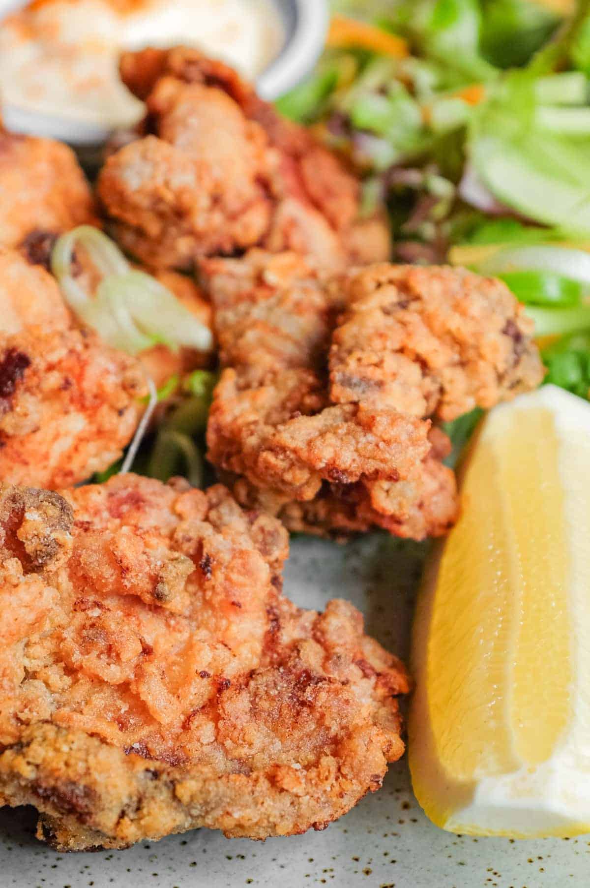 A plate of Japennese karaage chicken with a side salad, lemon wedge, and mayonnaise