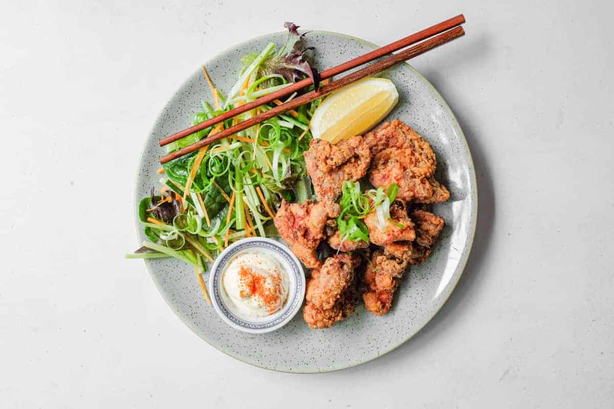 A plate of Japennese karaage chicken with a side salad, lemon wedge, and mayonnaise
