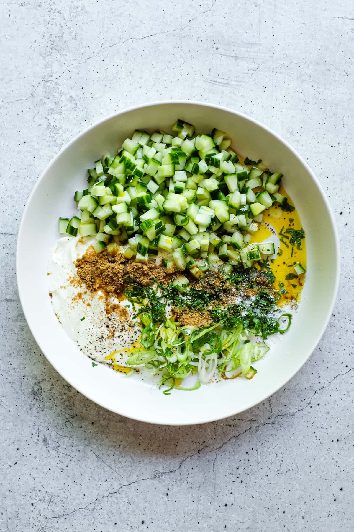The ingredients for creamy Indian yoghurt raita in a bowl, just before stirring.