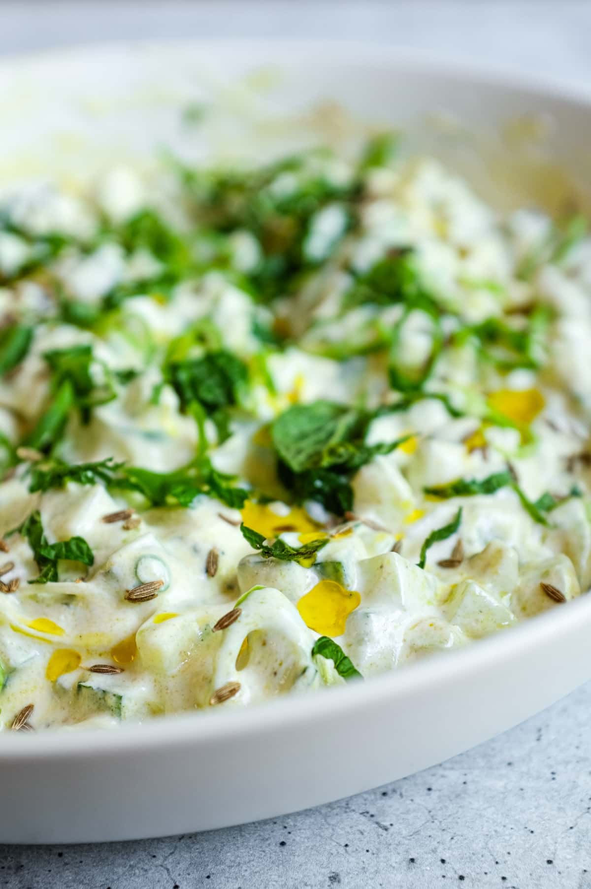 Indian yoghurt raita with cucumber, mint and spring onions in a small serving bowl