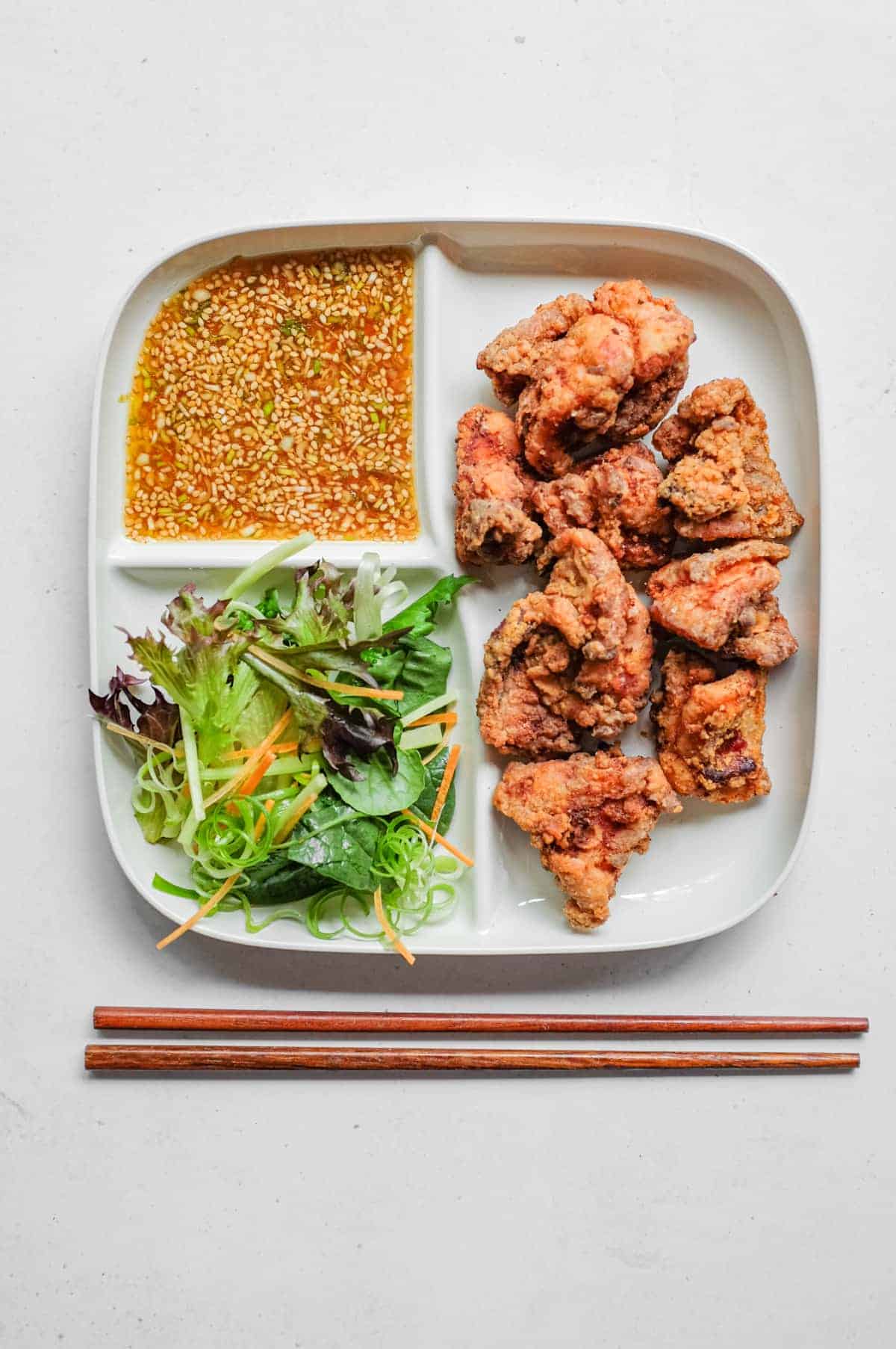 A compartmental plate which holds karaage chicken, yurinchi sauce and salad